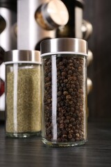 Different spices in glass jars on grey wooden table, closeup