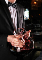 An Elegant Waiter Gracefully Presenting a Beautiful Decanter Filled with