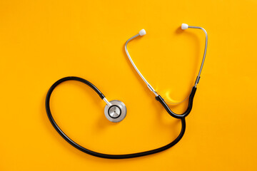 Stethoscope forming heart shape on yellow background promoting healthcare and medical services