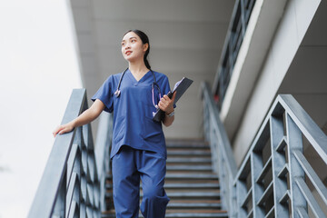 Young female doctor climbing hospital stairs holding patient chart