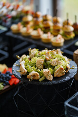 Chicken skewers with green salad served on a black stand for a festive buffet.