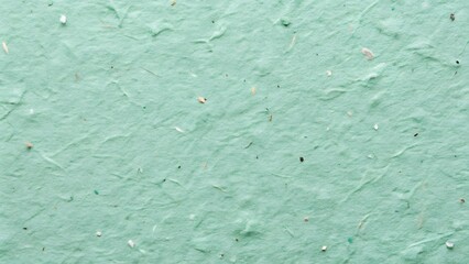 Close up textured background of handmade paper with subtle variations in pale green and white hues