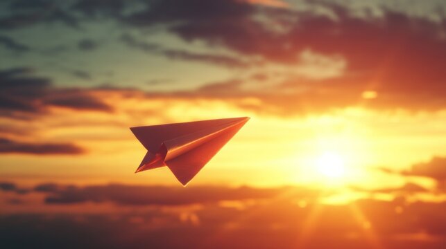 A paper airplane soars against a radiant sunset sky, symbolizing freedom and flight