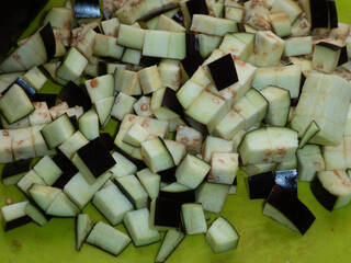 Diced Eggplant Cubes on a Green Cutting Board.