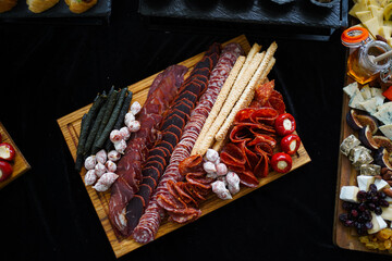 Buffet table with assorted snacks, cheese and meat platter, tartlets and canapés.