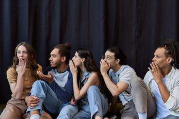 Group of friends expressing excitement and joy while whispering secrets in a playful atmosphere
