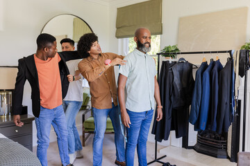 Friends helping groom try on outfits for wedding day, enjoying moment