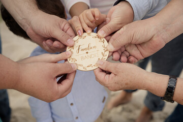 Familienh&auml;nde mit Holzschild &ndash; Liebe und Zusammenhalt am Meer