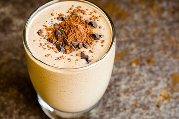 Creamy chocolate protein shake topped with cocoa powder and chocolate sprinkles in a cozy kitchen setting