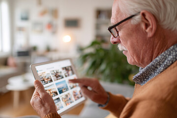 Senior man using tablet to browse digital content at home during the afternoon