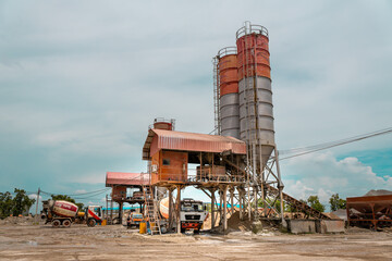 Construction site with cement factory, mixer trucks, and concrete silos