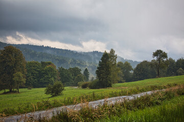 A cloudy day with a road running through a grassy field
