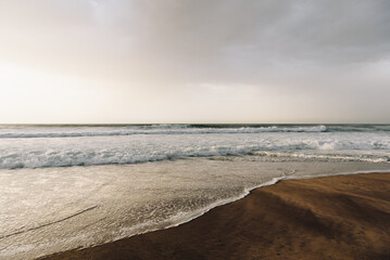 Ocean waves rolling onto the sandy shore at Cabo da Roca, Portugal