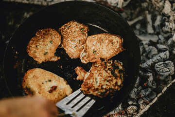 Golden Potato Pancakes Frying Outdoors on Campfire Skillet