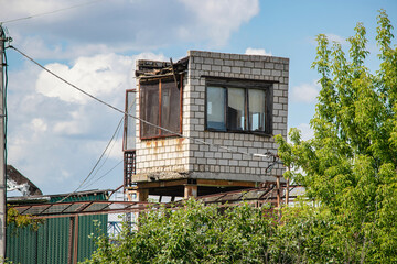 Unique building structure amidst greenery with blue sky and clouds during the day in an urban...