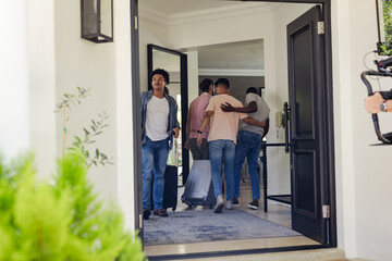 Friends arriving at home, carrying luggage and hugging, preparing for celebration