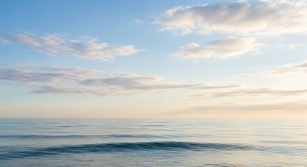 Calm ocean view under a light blue sky with soft, pastel clouds