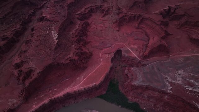 Aerial view of deep canyons with striking red rock formations carved by time, with roads winding through, Moab, Utah, United States.