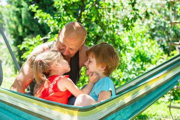 Cheerful family relaxing outside in the park, grandfather kissing grandchildren 