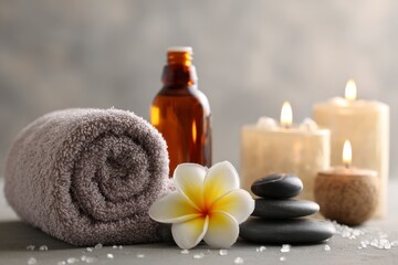 Spa scene towel oil flower stones candles on a gray surface with scattered crystals