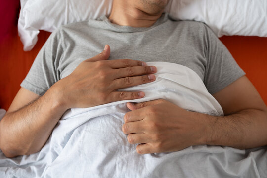 Man, sleeping and bed in morning rest for healthy wellness, peace and quiet on comfort pillow at home. Tired or exhausted male person asleep or dreaming on peaceful holiday or weekend in the bedroom