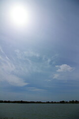 眩しい真夏の太陽と水辺の風景