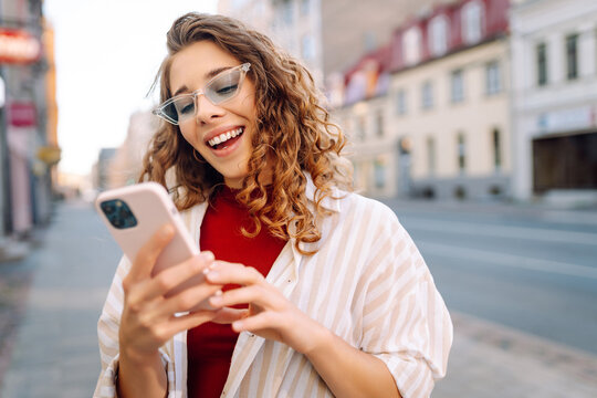 Portrait of a young woman with a phone and sunglasses enjoying the sunset. A beautiful woman with a phone enjoys the sunset outdoors. Leisure concept. Lifestyle.