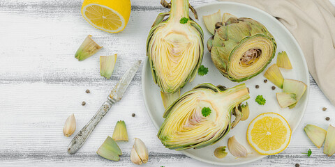 Fresh green artichokes cooking on wooden background. Traditional seasonal ingredients