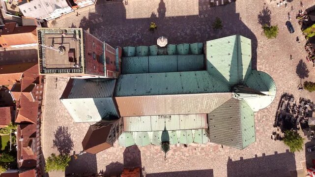 Aerial view of the impressive Ribe Cathedral, its copper and brick roofs contrasting with the surrounding cobblestone square, Ribe, Denmark.
