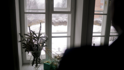 Christmas decorations resting on windowsill during gentle snowfall