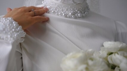 Bride showing wedding ring and dress embellished with pearls