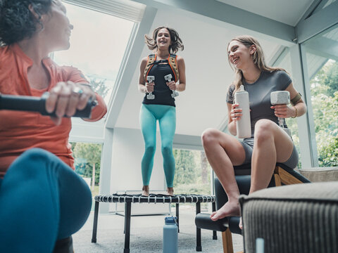 Family exercising together in living room with trampoline and weights