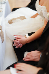 Newlyweds sitting together and holding hands during the wedding dinner.
