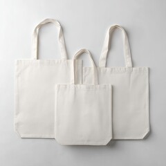Three off-white canvas tote bags of varying sizes, arranged on a light grey background