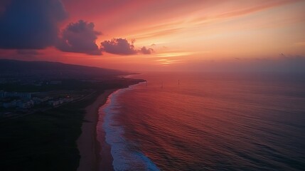 Aerial view of a vibrant sunset over a coastline with city in the distance