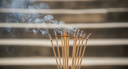 Incense sticks burning with smoke rising against a blurred background.