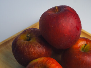 Fresh red apples on a wooden tray, close-up