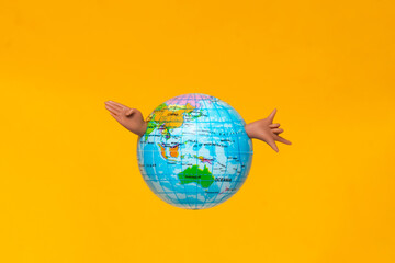 Naklejka premium Globe with joyful arms celebrates global fun and exploration against a bright yellow background