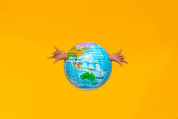 Naklejka premium Globe held joyfully with hands against a vibrant yellow background
