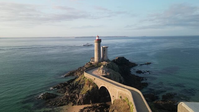 Aerial view of the Pointe du Minou lighthouse standing tall on a rocky outcrop connected by a stone bridge, surrounded by the sea, Plouzan&eacute;, France.