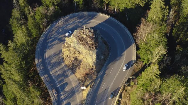 Aerial view of the Kreuzfelsenkurve road winds around a rock formation amid a dense forest creating a striking contrast between nature and infrastructure, Breitnau, Baden-W&uuml;rttemberg, Germany.