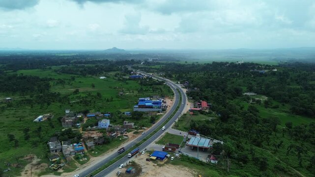 Aerial view of a highway cutting through lush greenery, where the road stands out against the verdant landscape, Bundu, Jharkhand, India.