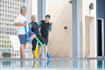 Senior Adults Doing Water Aerobics with a Trainer, Active Elderly People Exercising with Pool Noodle, Group Aqua Fitness Class for Older Adults