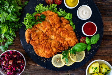 Garnished wiener schnitzel with ketchup, mayonnaise and mustard on wooden table