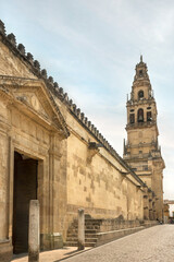 Fototapeta premium Medieval cobblestone street in Cordoba, Spain, with entrance to antique Mosque-Cathedral and Bell tower. Spanish famous touristic attraction. Beautiful European travel destination. Religious monument.