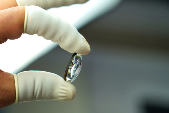 In camera lens production, an expert employee checks the camera lens.