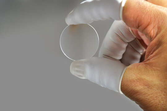 In camera lens production, an expert employee checks the camera lens.