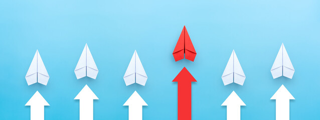 Business competition concept. Red paper plane leading among a white planes and arrow on blue background