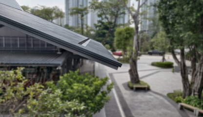Low-angle, eye-level shot modern sloped roof with textured panels and streamlined design. background intentionally blurred, showing an outdoor urban landscape with trees, walkway