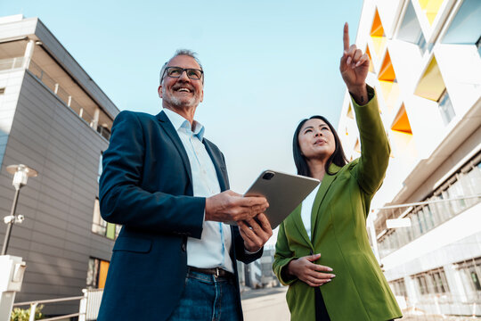 Business colleagues discussing project outdoors with tablet and gesture